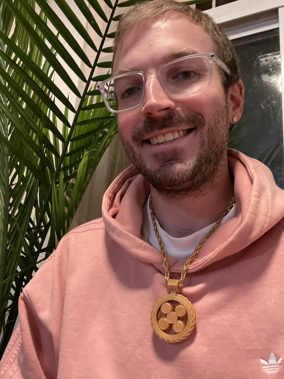 Lewis in a pink hoodie wearing the gold v2 planetary pendant on a rope chain